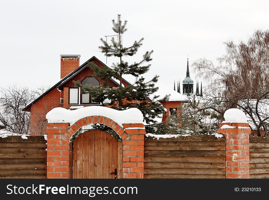Front wall of red brick with a fence in snow. Front wall of red brick with a fence in snow