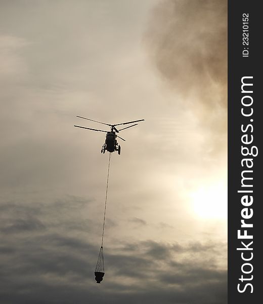 Helicopter extinguishes the fire with water. Helicopter extinguishes the fire with water