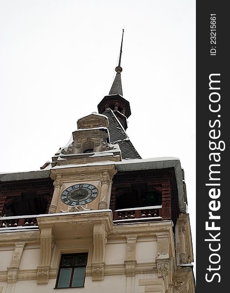 A clock on a medieval castle tower covered in snow. A clock on a medieval castle tower covered in snow