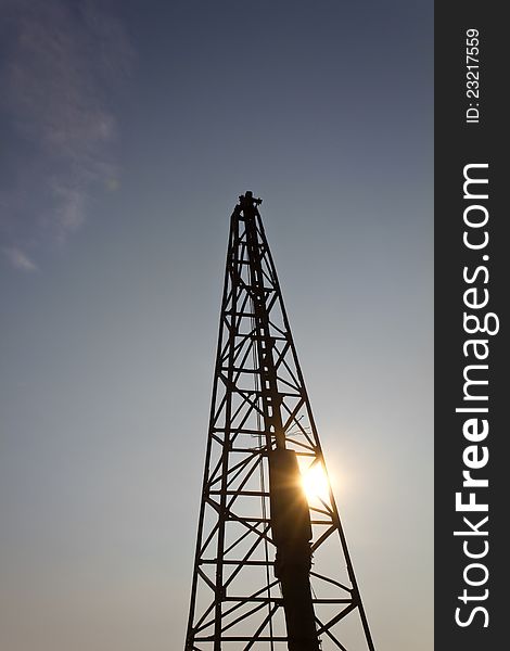 Silhouette of a worker in a Derrick, with sun shining through. Silhouette of a worker in a Derrick, with sun shining through.