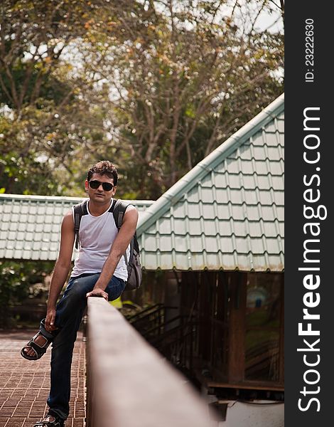 Happy indian man sitting on railing of house