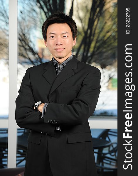 Young Asian Businessman with arms crossed inside an office building