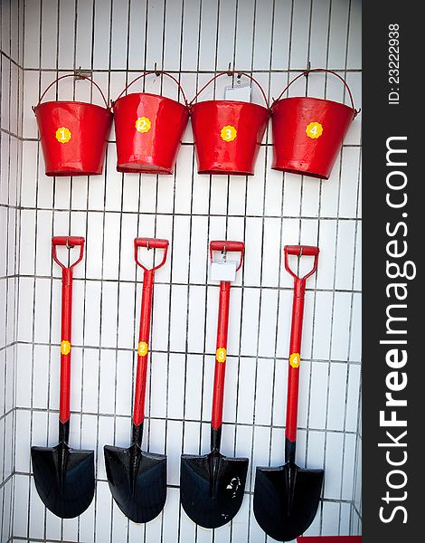 Red shovels and pails neatly hang on the wall. Red shovels and pails neatly hang on the wall
