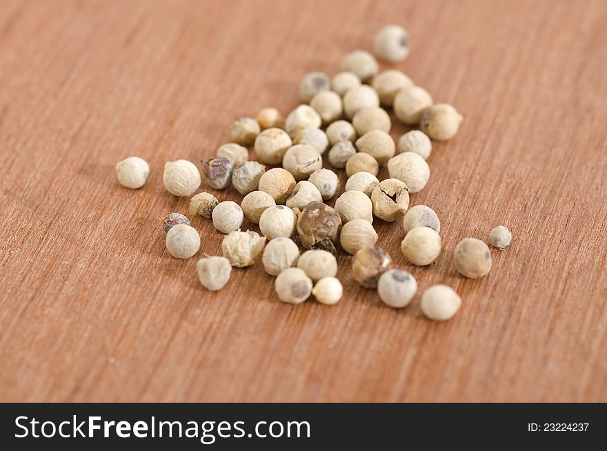 White pepper seeds shot over wooden background