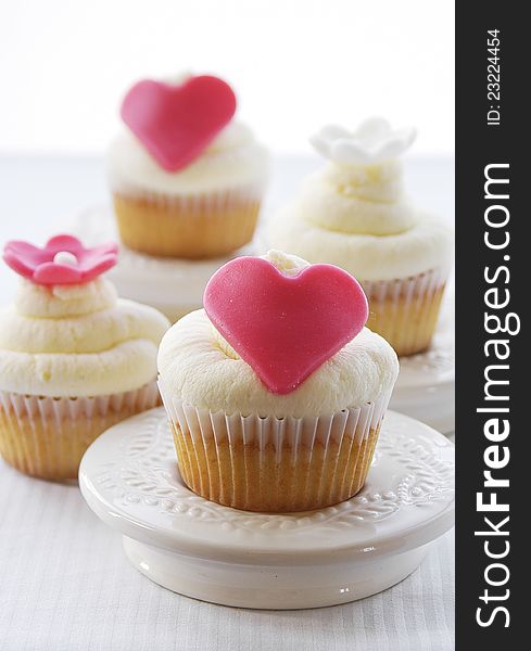 Fresh vanilla cupcakes with marzipan hearts and flowers as decoration. Fresh vanilla cupcakes with marzipan hearts and flowers as decoration