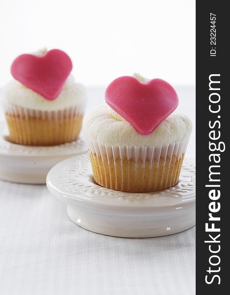 Fresh vanilla cupcakes with marzipan hearts as decoration. Fresh vanilla cupcakes with marzipan hearts as decoration