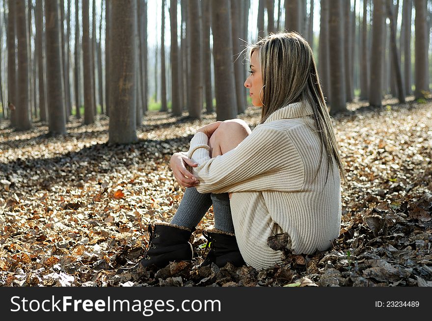 Blonde gir sitting in a forest of poplars