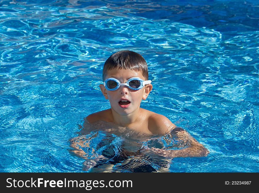 Boy with spectacles in the swimming pool with clear water