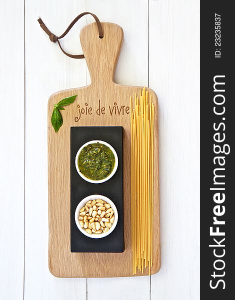 Basil pesto and pinenuts and spagetti on a wooden board