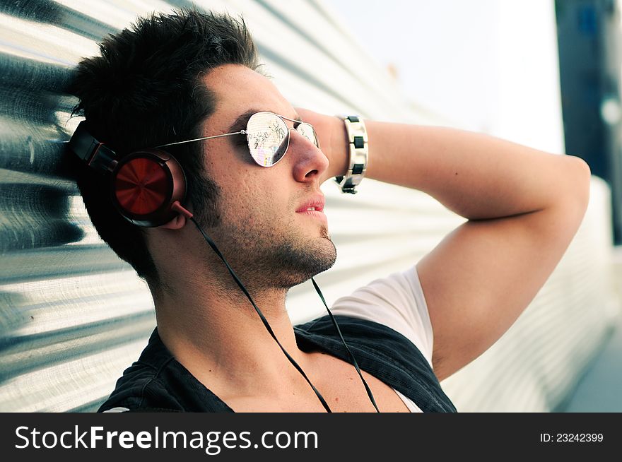 Portrait of handsome man in urban background listening to the music with headphones. Portrait of handsome man in urban background listening to the music with headphones