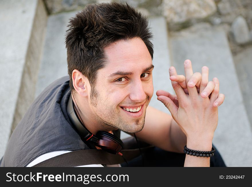 Portrait of young smiling man sitting on steps, with headphones. Portrait of young smiling man sitting on steps, with headphones