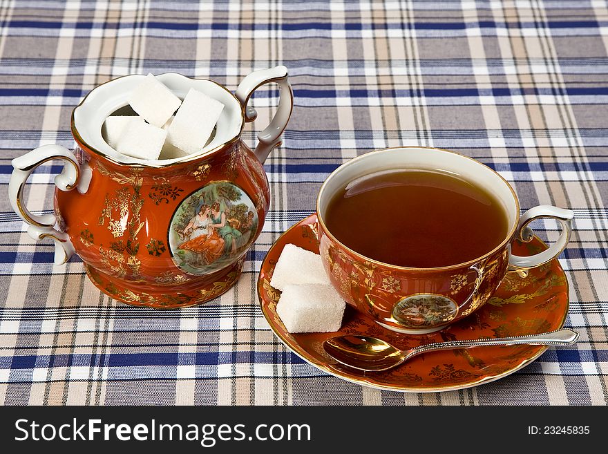 Cup of tea and a sugarpot on the checked tablecloth, studiolights. Cup of tea and a sugarpot on the checked tablecloth, studiolights