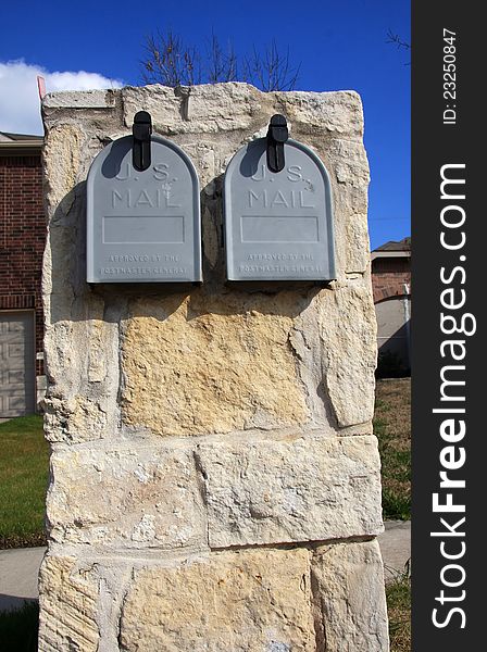 It is a double grey mailbox in the front yard. It is a double grey mailbox in the front yard.