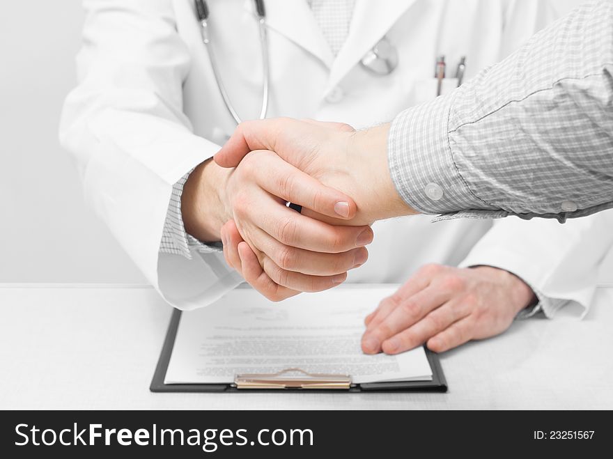 Doctor with stethoscope and clipboard shaking patients hand