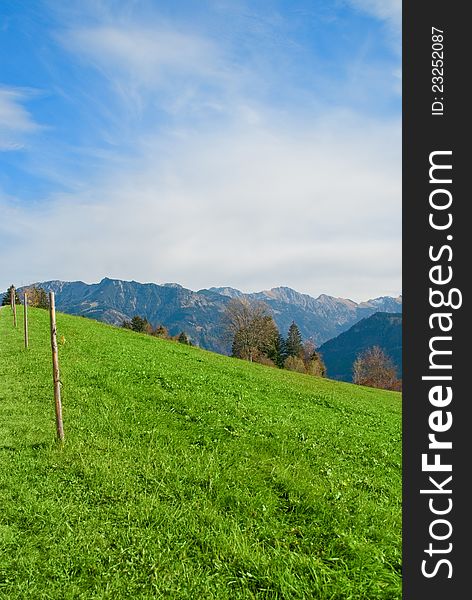 Alps meadow with light fence and blue sky background