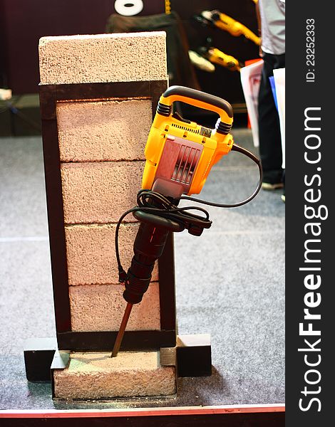 Yellow Demolition Hammer Breaking Brick in a demonstration. Yellow Demolition Hammer Breaking Brick in a demonstration