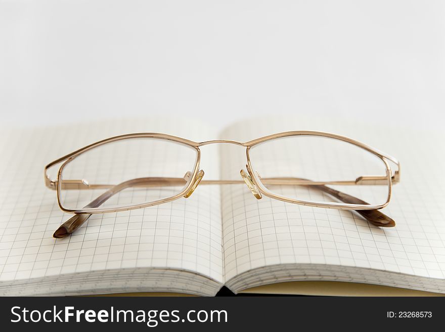 Glasses and notebook on the white background