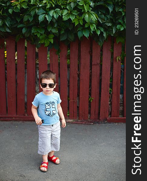 Cool boy wearing sunglasses, standing outdoors on sidewalk. Cool boy wearing sunglasses, standing outdoors on sidewalk