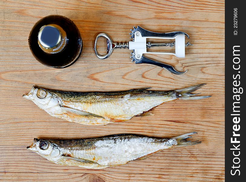 Dry salty fish and beer on a wooden background
