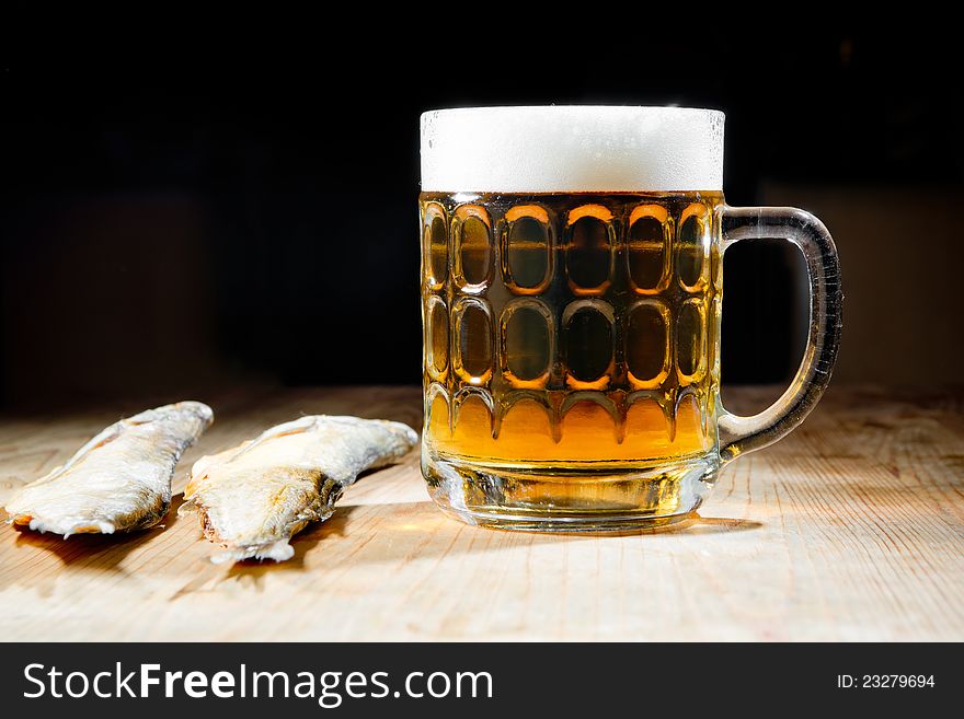 Beer with dry salty fish on a dark background