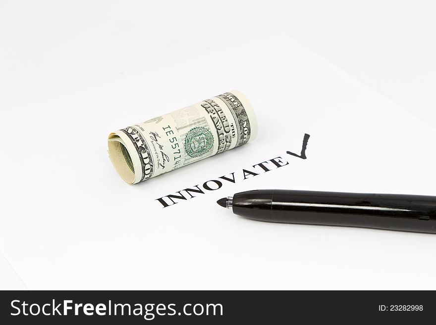 The word, innovate, is printed out with a black check next to it and rolled US currency above.  Black felt tip pen is on the right;