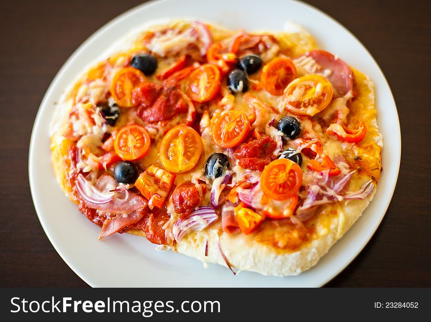 A pizza coated with salami, olives, onions and tomatos. A pizza coated with salami, olives, onions and tomatos