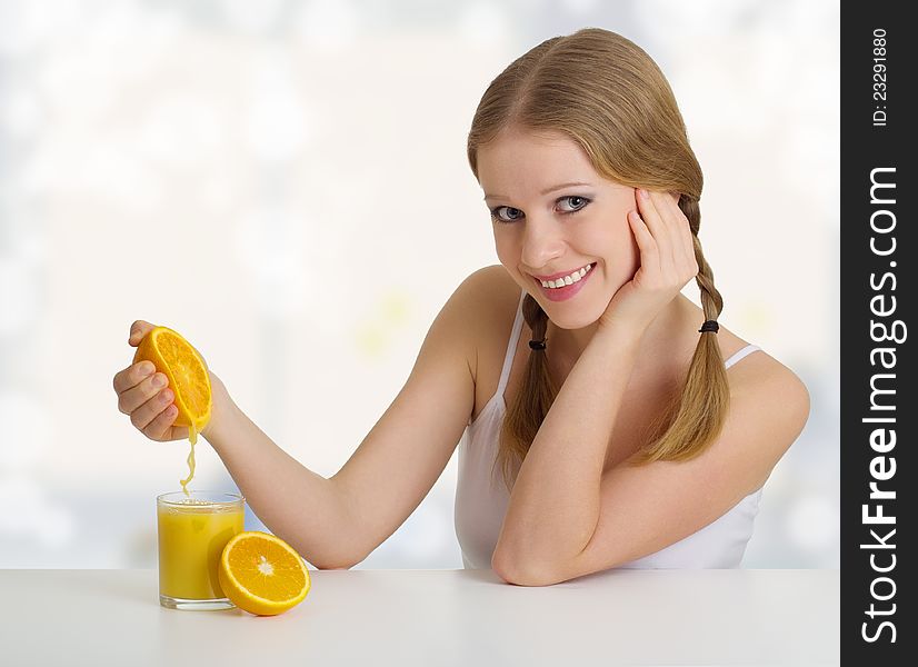 Beautiful girl squeezes the juice from the orange