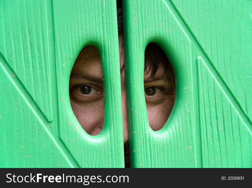 Young man looks through the window of a dolls house. Smiling man. Man eyes.