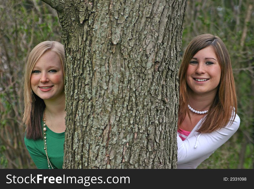 Girls Peeking Around a Tree smiling big