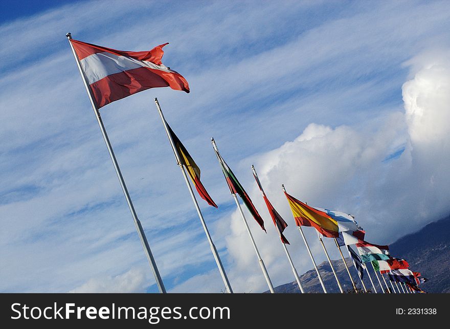 A row of european national flags with blue sky and clouds on background