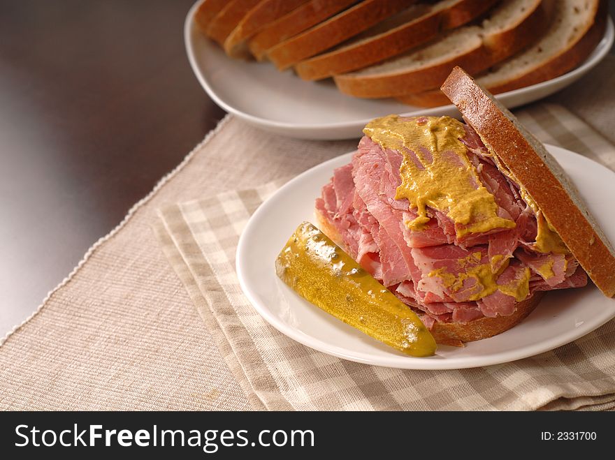 A corned beef sandwich with mustard on rye bread