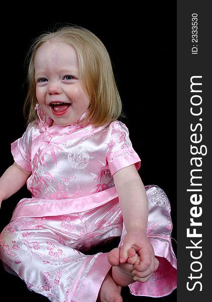 Little girl laughing sitting on a black background