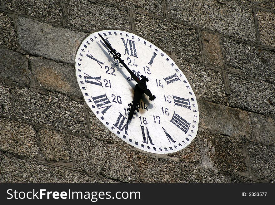 Old wall clock in a stoned wall