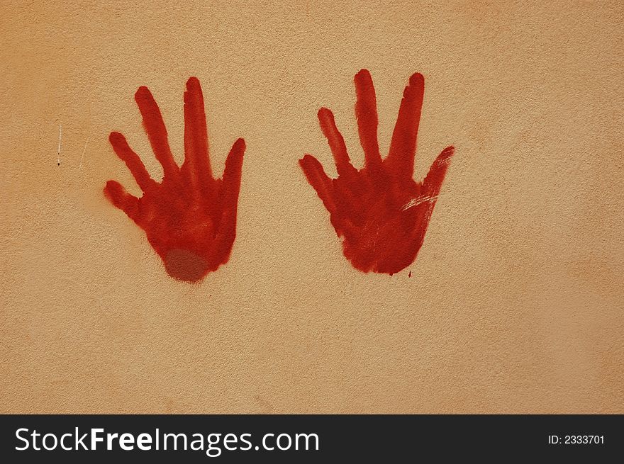 Red hands painted on a wall with artistic effect. Red hands painted on a wall with artistic effect