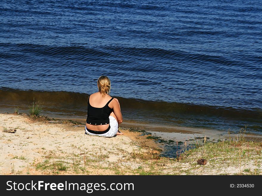 Girl sitting alone staring into the water. Girl sitting alone staring into the water