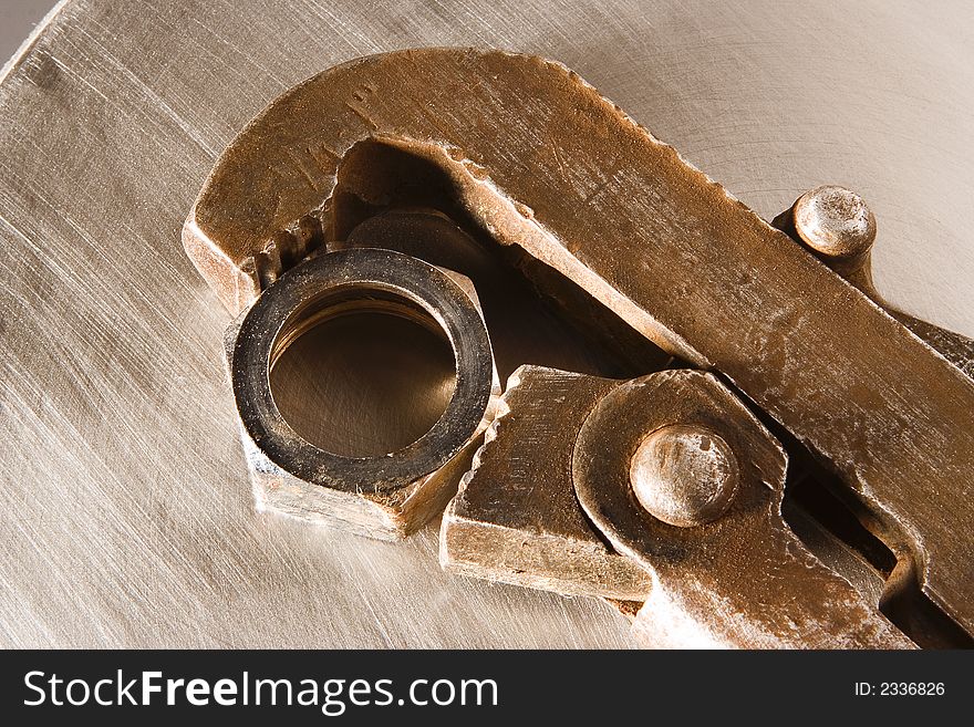 The wrench and nut lays on a metal sheet