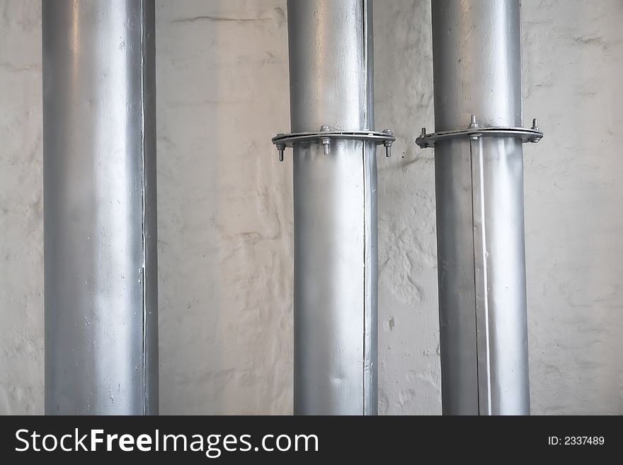 Gray industrial pipes over white brick wall