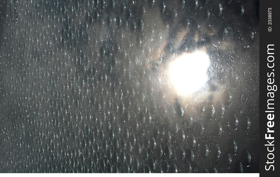 Water drops on a window with the sun reflecting in the glass. Water drops on a window with the sun reflecting in the glass.