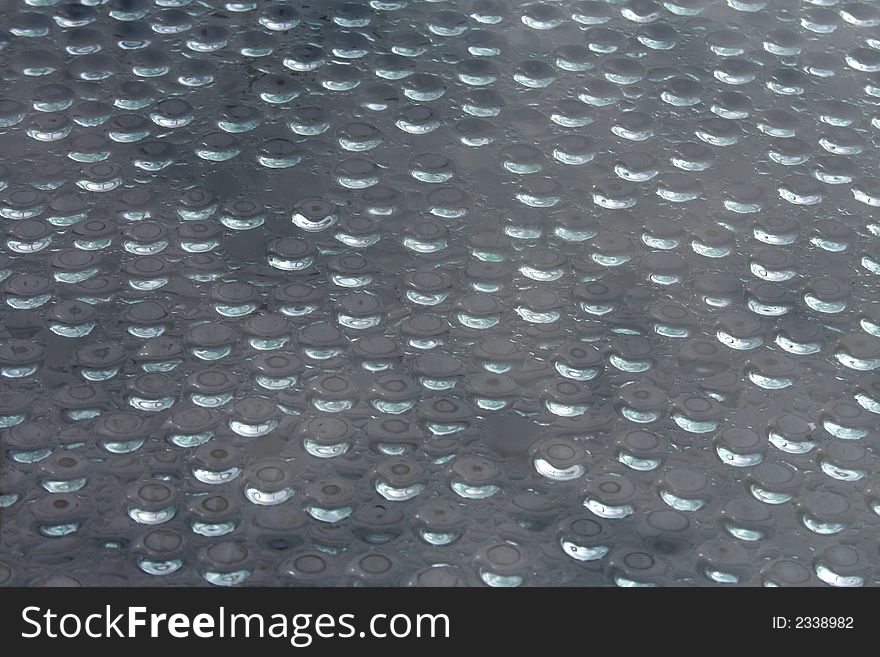 Water drops on a window with reflections from the sun.