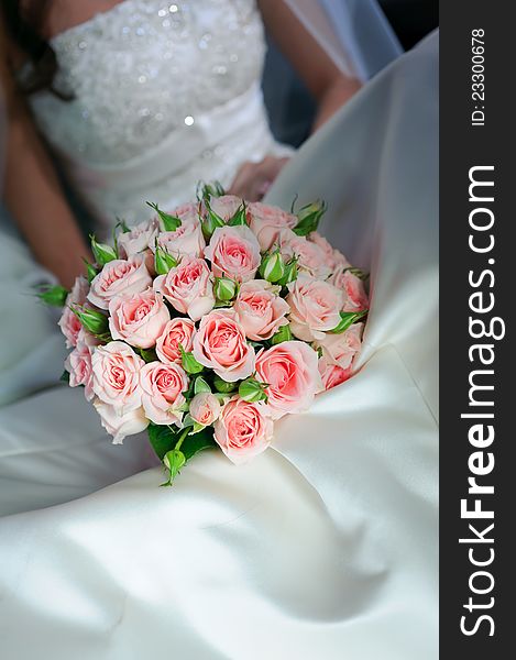 Bride in a white dress holding bouquet of roses