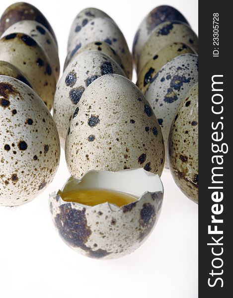 Quail eggs with one open on a white background