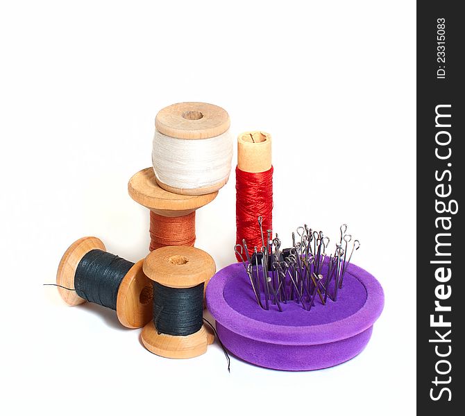 Group of spools with thread and needle bed  on white