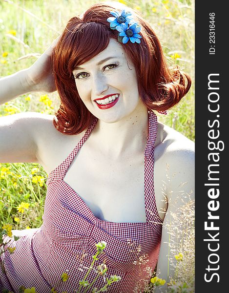 Beautiful red head pin up model sitting in a field. Beautiful red head pin up model sitting in a field