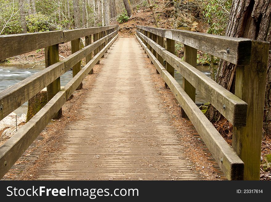 A wooden bridge crosses over a little white water creek. A wooden bridge crosses over a little white water creek.