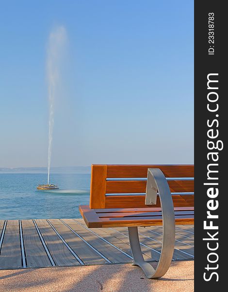 Modern benches along the coastline of Lake Garda. Benches and a fountain in the lake. (Bardolino,Italy). Vertically. Modern benches along the coastline of Lake Garda. Benches and a fountain in the lake. (Bardolino,Italy). Vertically.