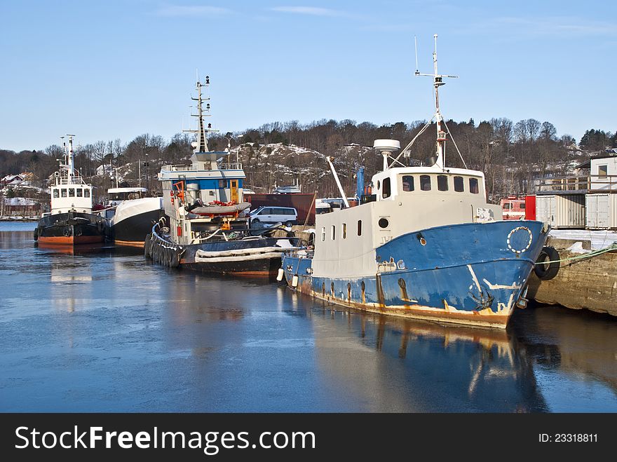 Fishing boats and tugboats moored to the docks at the port of Halden. Fishing boats and tugboats moored to the docks at the port of Halden.