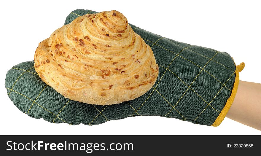 A baker’s hand in an oven mitt holding a freshly baked bun on a white background. A baker’s hand in an oven mitt holding a freshly baked bun on a white background