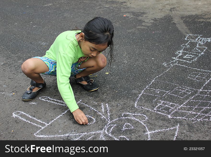 A female children was drawing on the street. A female children was drawing on the street.