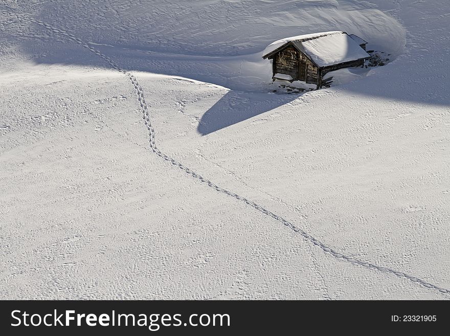 Snowbound hut with snow shoe tracks in front of the hut