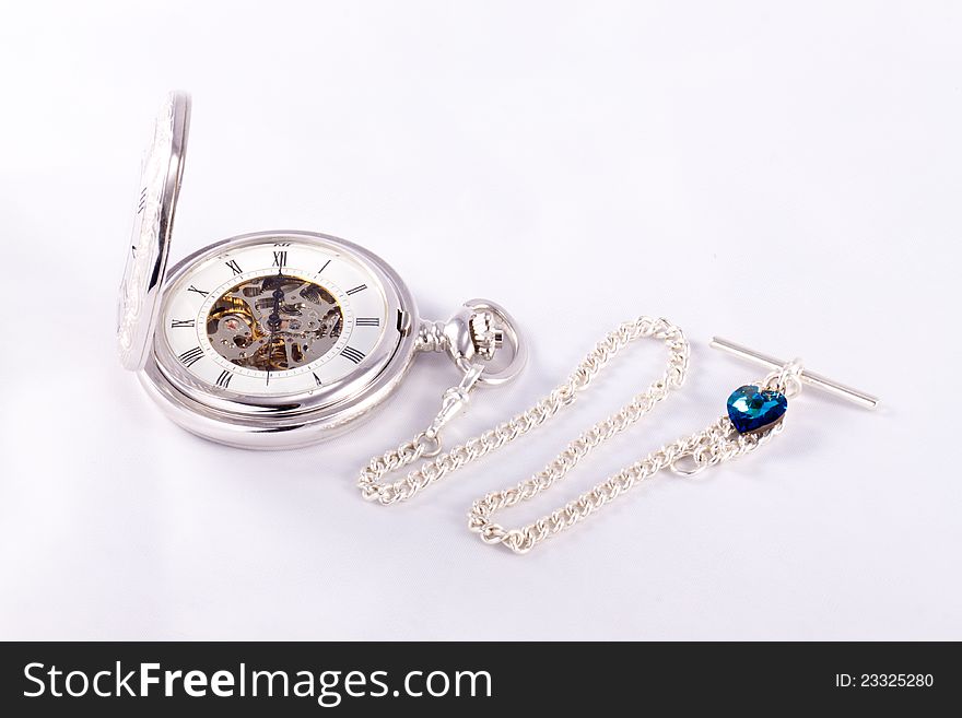 A silver pocketwatch and chain set against a white background. A silver pocketwatch and chain set against a white background.